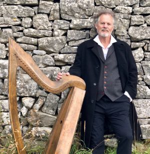 Patrick Ball and harp by stone wall